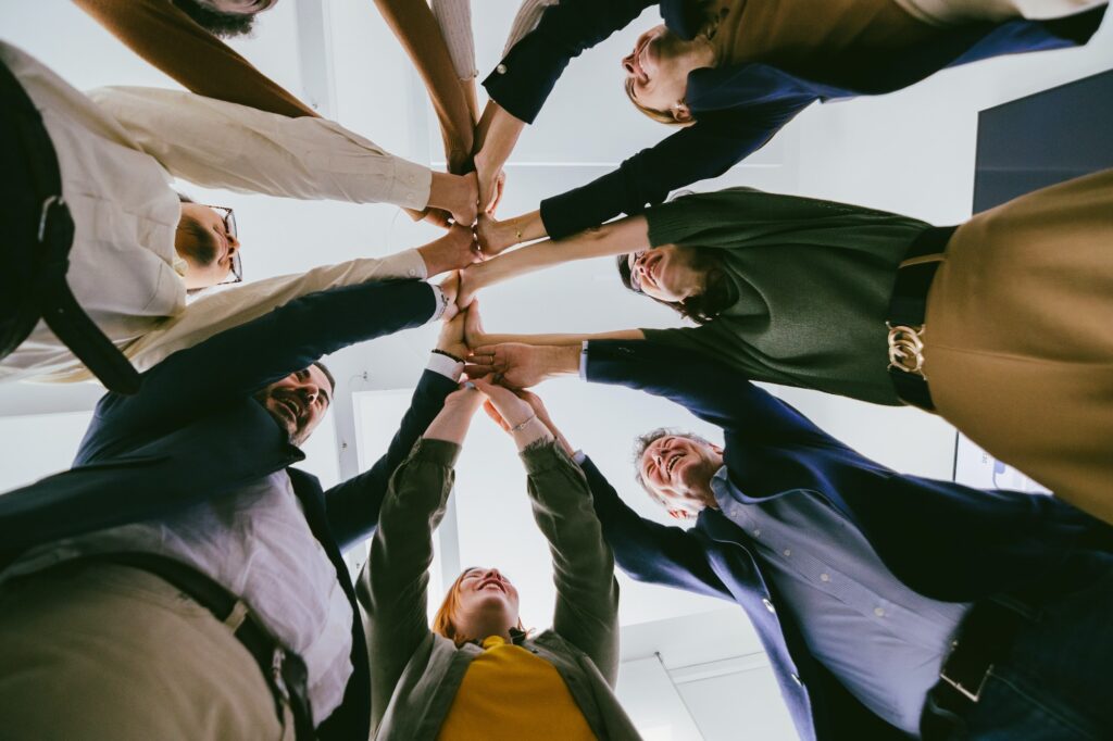 bottom view of united colleagues standing In circle holding hands together